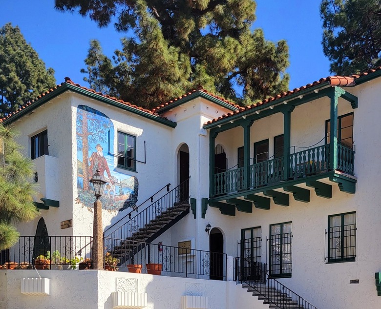 White Spanish style building with red tile roof and green balcony trim