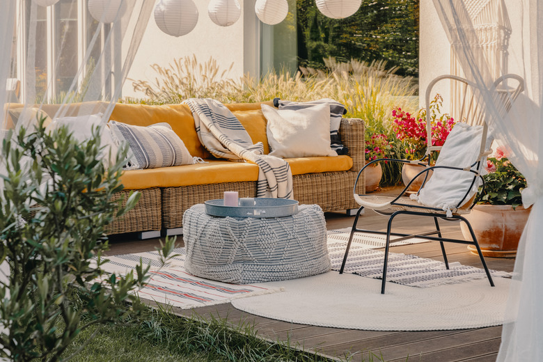 Real photo of an armchair, pouf as a table, and wicker couch on a terrace.