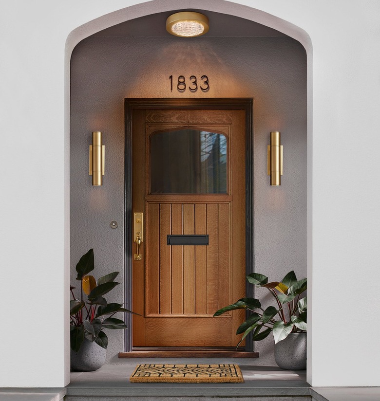 A wooden door with a brass handleset and matching brass vertical lights