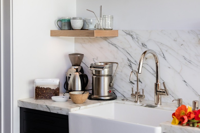 Granite kitchen backsplash and counter with sink under a shelf with glassware