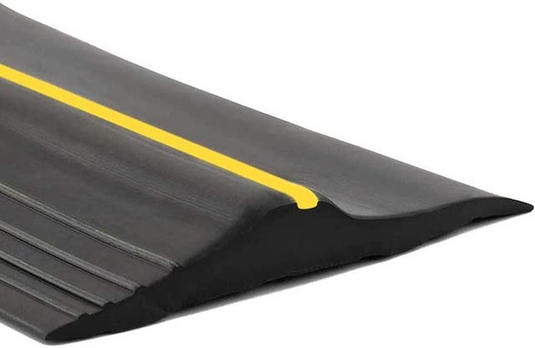 A black rubber garage door threshold with a yellow stripe down the middle