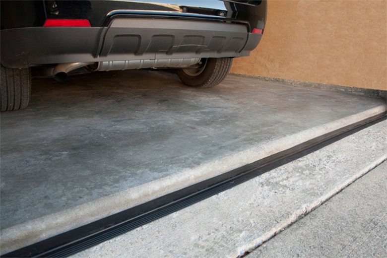 A black garage door threshold installed; a black car is parked in the garage