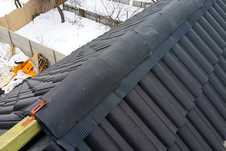 Installation of the roof of the house from ceramic black tiles.