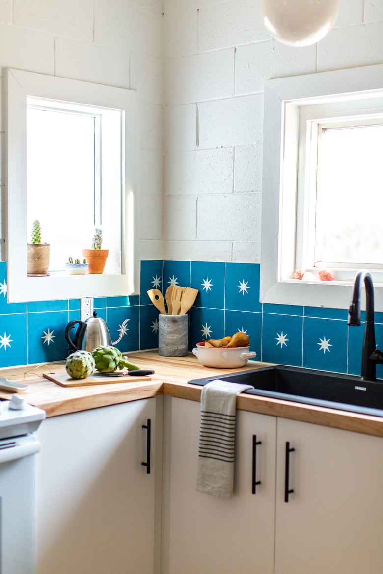 the corner of a kitchen with white walls, white cabinets, and an azure tile backsplash