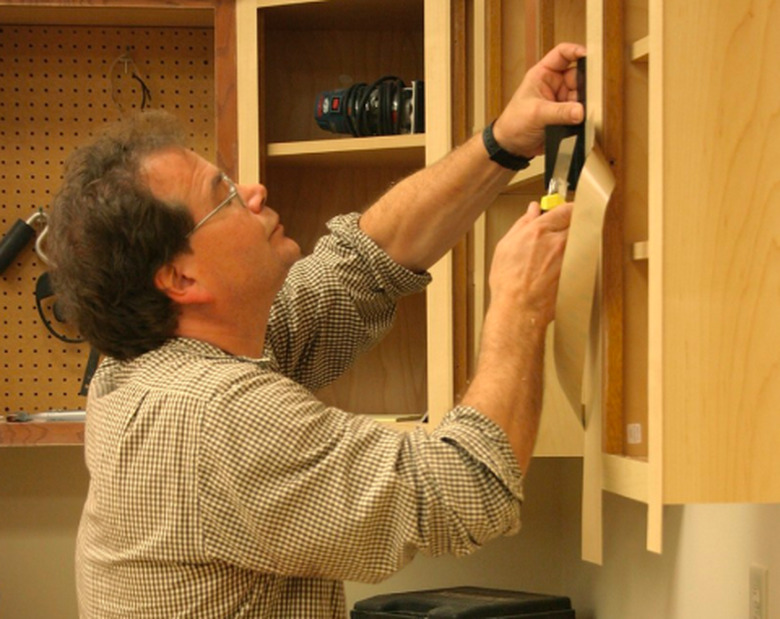 Man refacing cabinets.