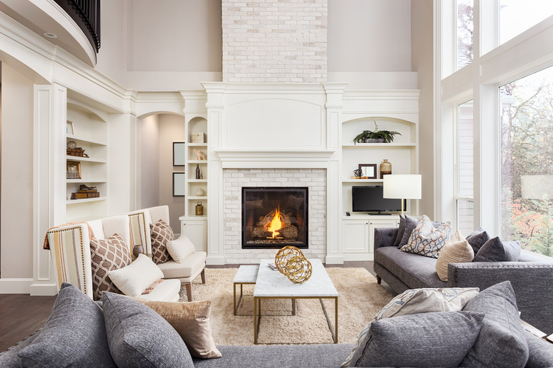 Living room interior with vaulted ceiling, loft area, hardwood floors, and fireplace.