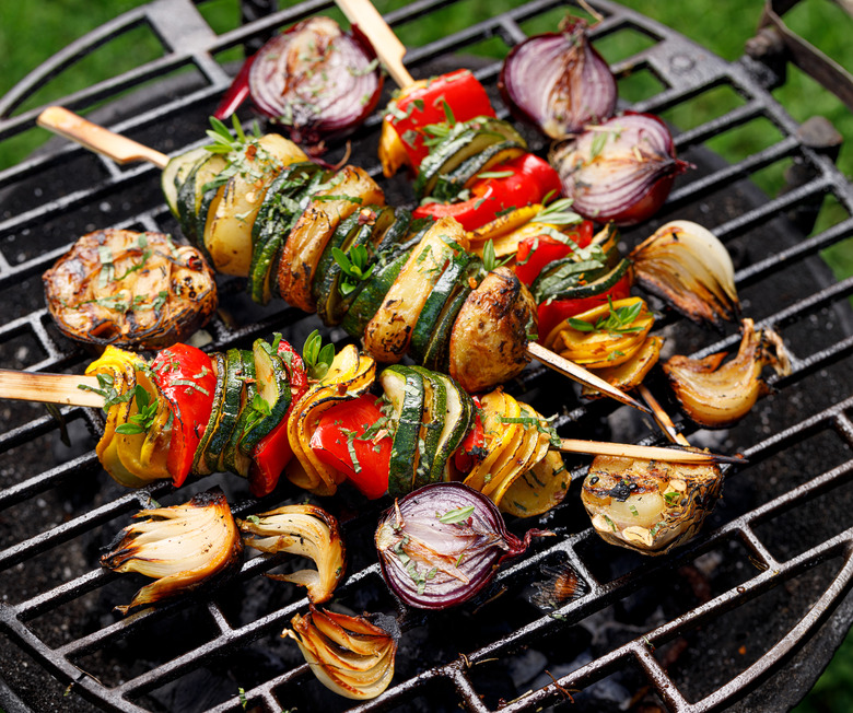 Vegetarian skewers, grilled vegetable skewers of zucchini, peppers and potatoes with the addition of aromatic herbs and olive oil on the grill outdoors.