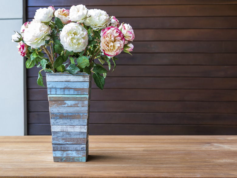 Artificial flowers with rustic wooden vase in modern interior room