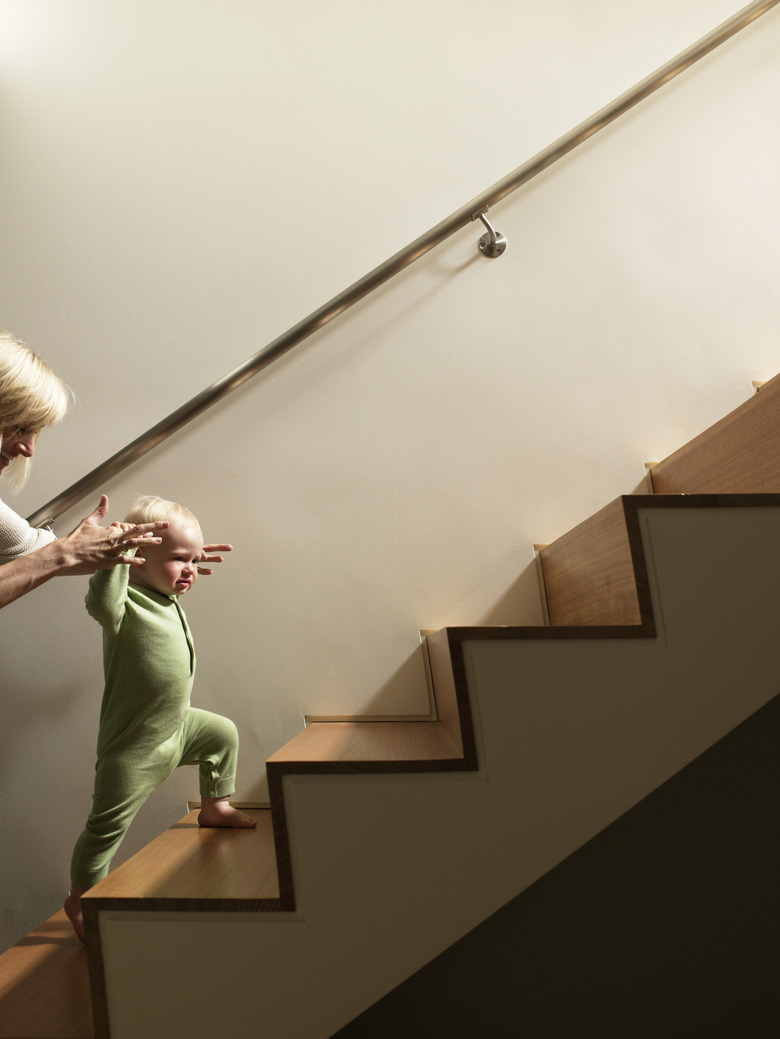 Mother helping baby boy walk up stairs