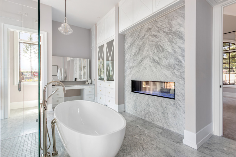 Stunning master bathroom interior in luxury home with bathtub, shower, and fireplace.