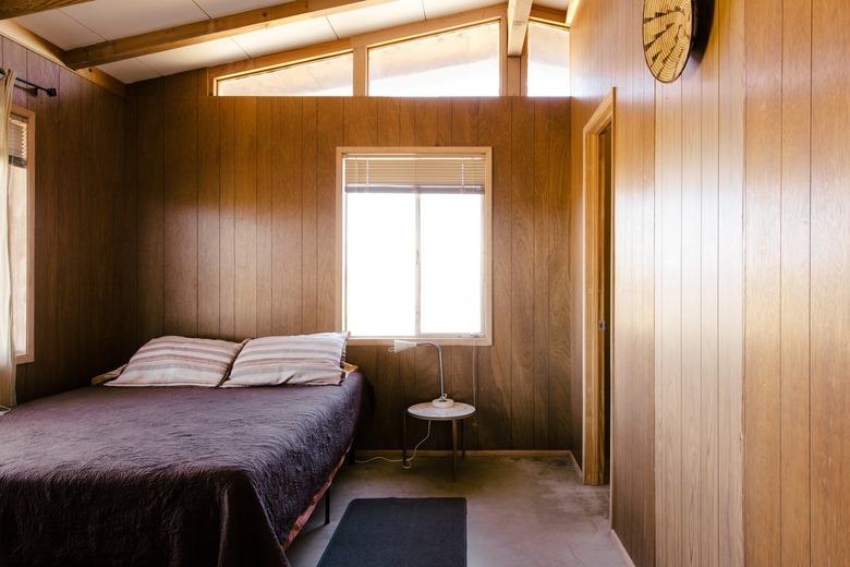 a bedroom with a modern sloping ceiling and retro wood paneling on the walls