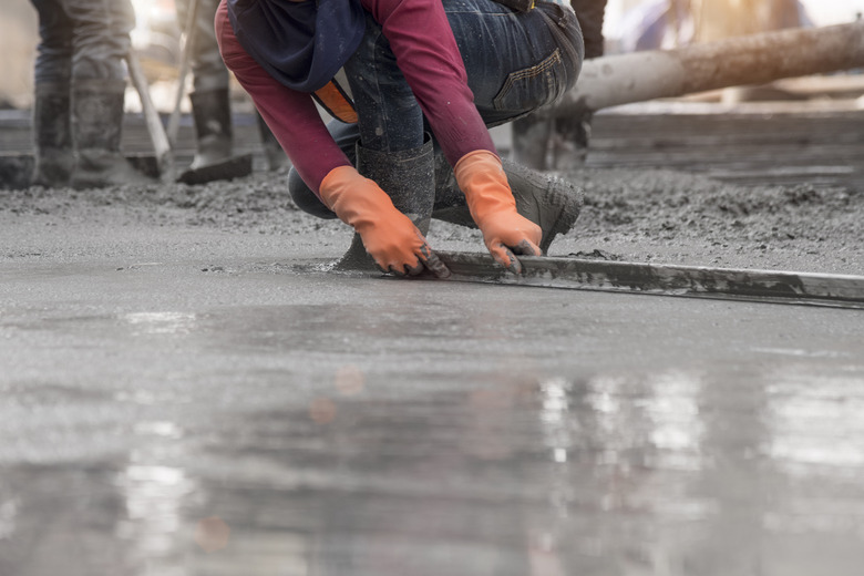 Construction worker troweling wet concrete.