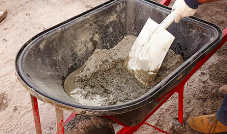 Mixing concrete in a wheelbarrow.