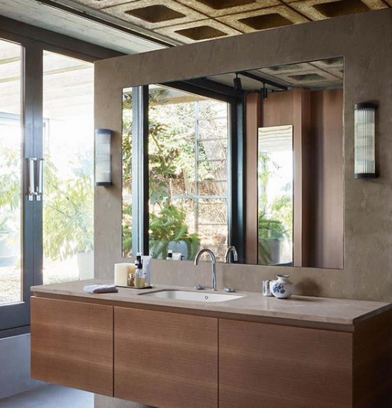 solid surface bathroom countertop with floating wood vanity and large frameless mirror