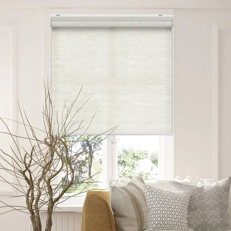 A couch with a window behind it, covered with light filtering roller shades