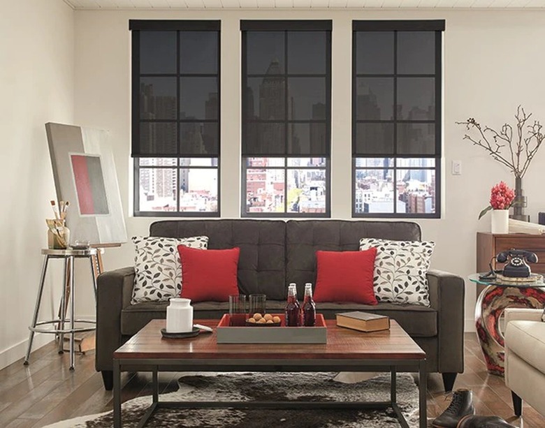 Three solar shades hung on three small windows in a living area