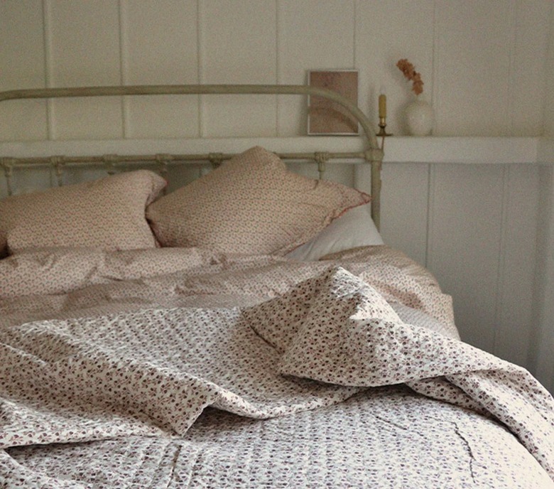 messy farmhouse-style bed with floral quilt