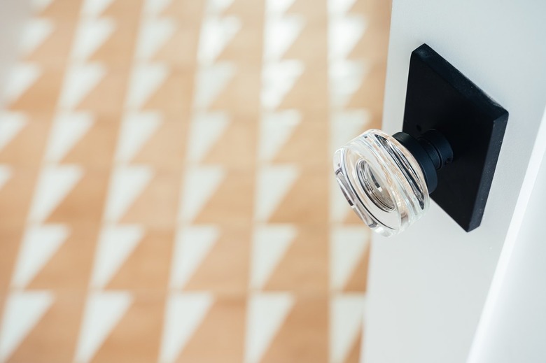 Clear crystal doorknob on a white door with floor tiles