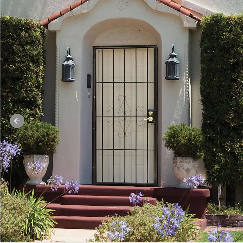 Security screen door on front door of a white house with red steps