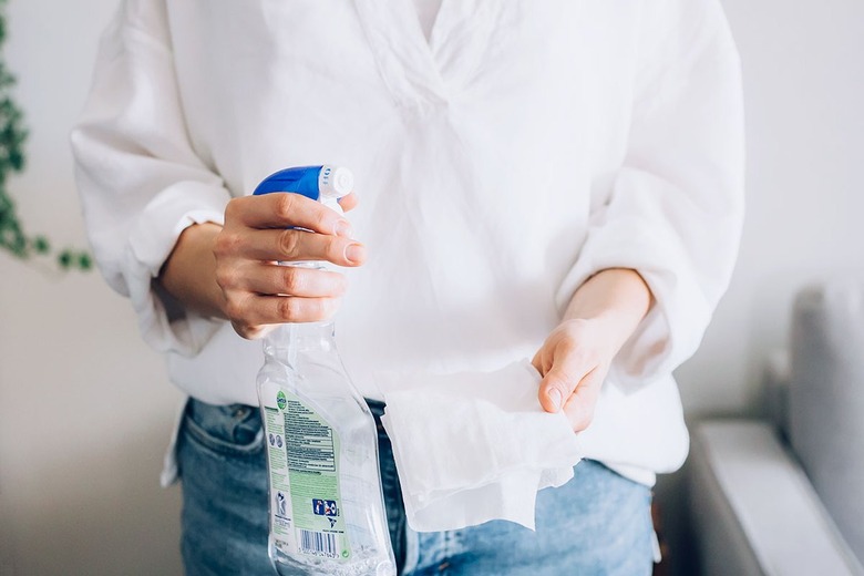 Hands holding cleaner spray bottle and sanitary wipe