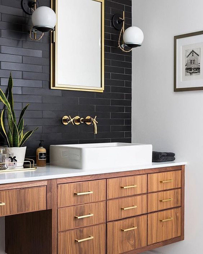 white bathroom countertop with warm wood vanity cabinet and black tile backsplash