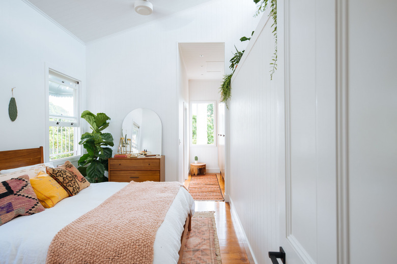 white bohemian bedroom with potted plants and coral accents