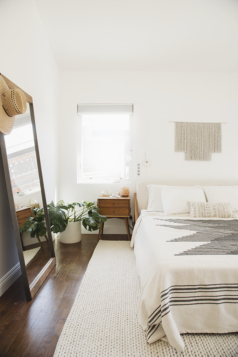 white bohemian bedroom with wall hanging and boho throw.