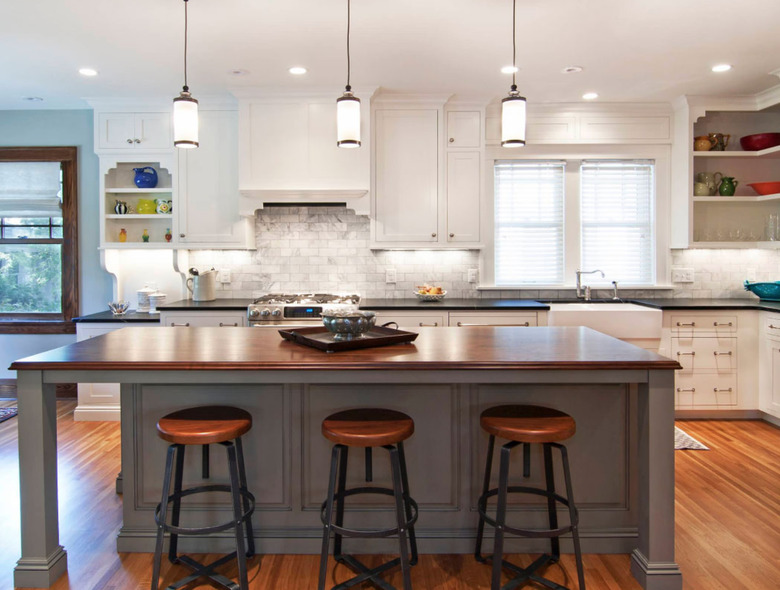 Gray kitchen island with wood countertop and wood bar stools.