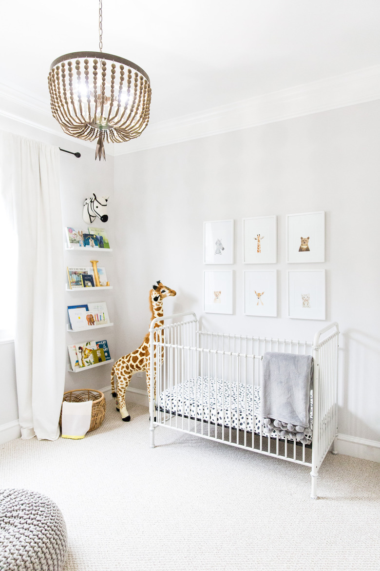 white nursery with framed prints of baby animals and beaded chandelier