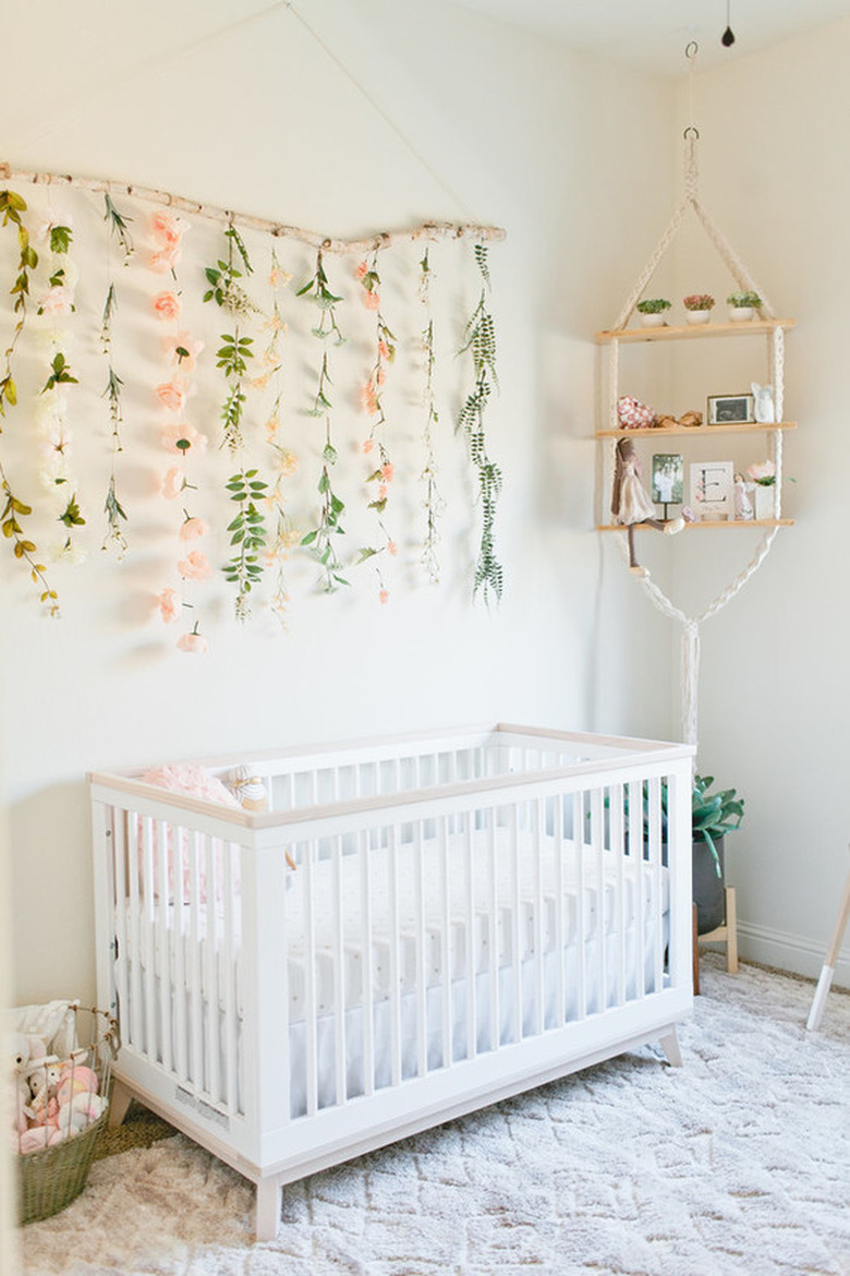 white boho girls nursery with floral wall hanging