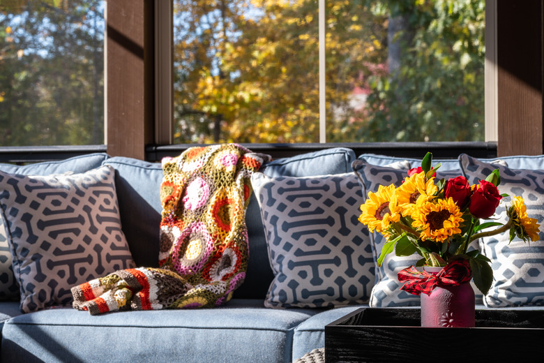 Corner of screened porch with comfortable furniture and flower pot.