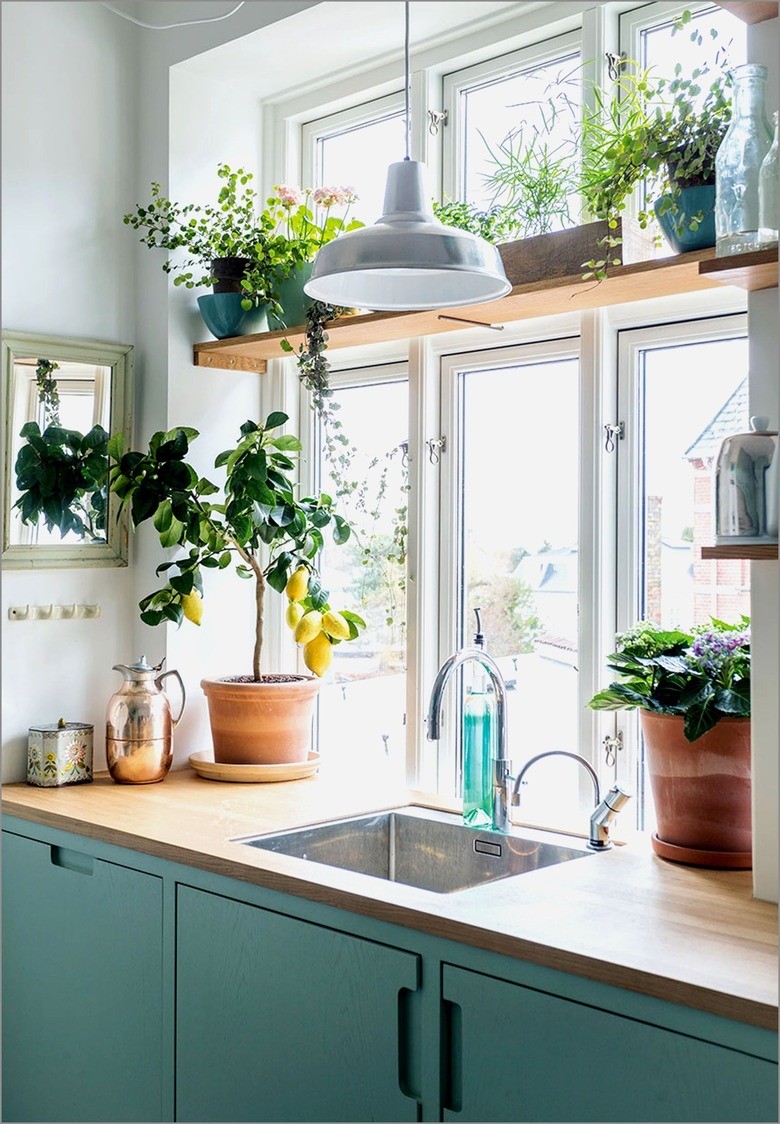 green and white kitchen with wood window plant shelf