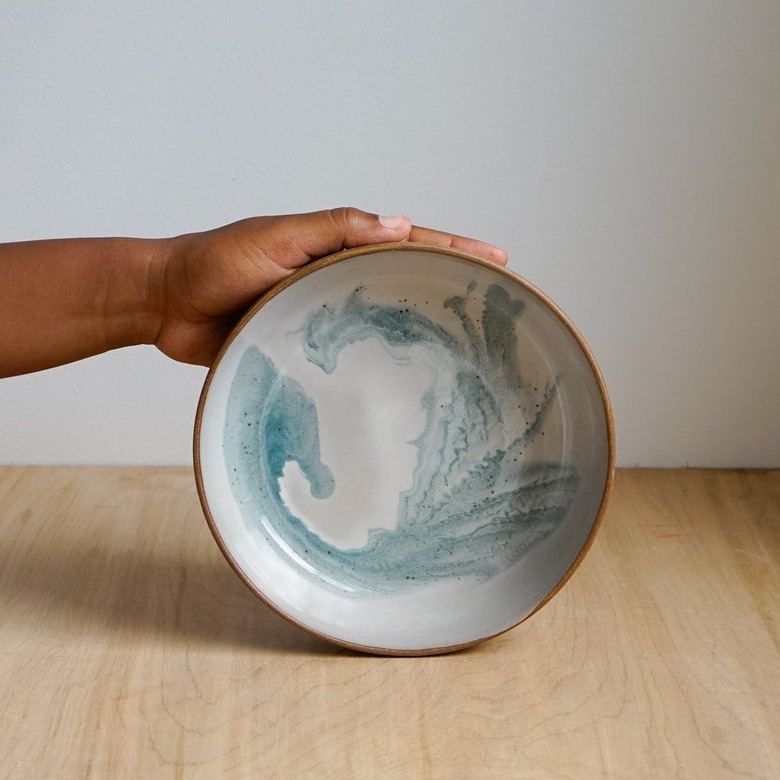 person holding bowl with blue swirl design