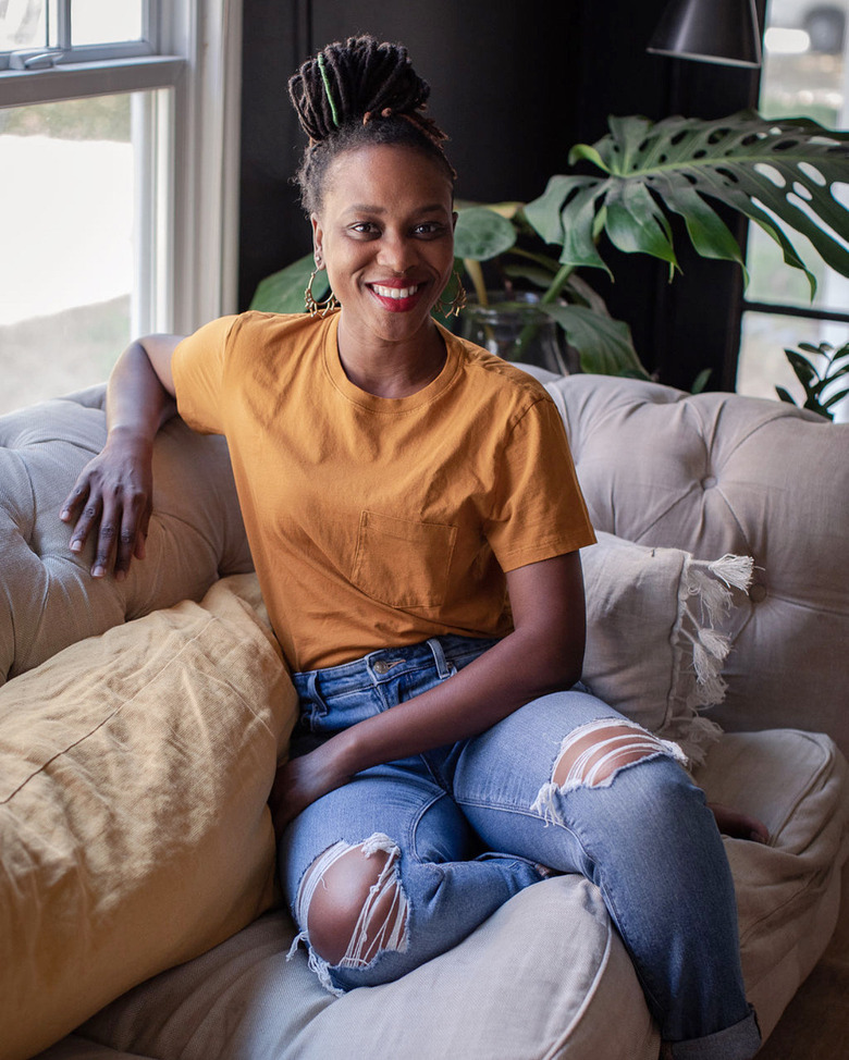 designer Shavonda Gardner on beige couch with yellow pillow