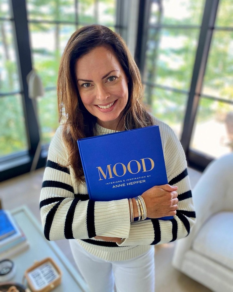 Anne Hepfer in a cream and black striped sweater holding her book 