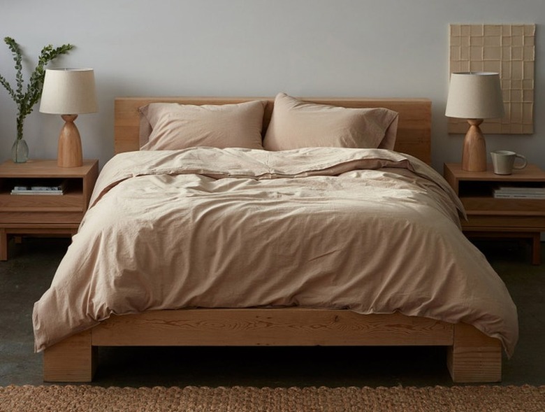 pink neutral bedding on light wood bedframe