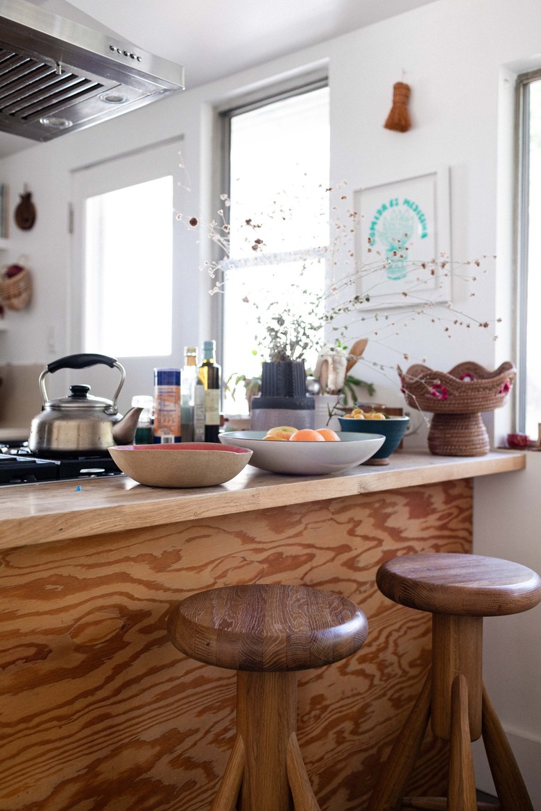 A wood countertop with wood stools in a white-walled kitchen