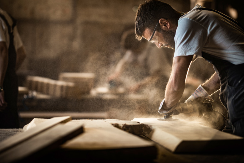 Carpenter using sander while working on a piece of wood.