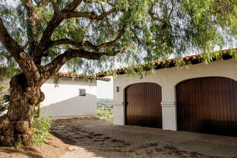 set of arched wooden garage doors with brick driveway