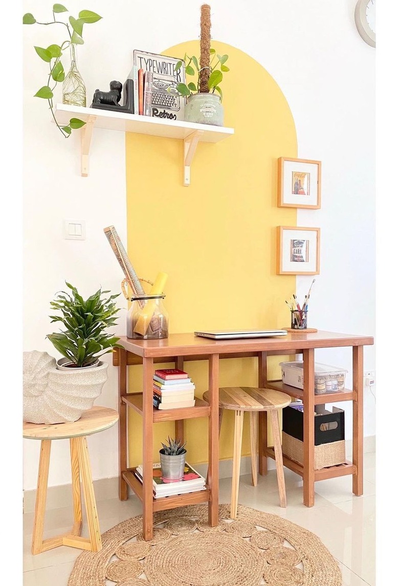 white home office with yellow accent wall, floating shelf on the wall with plants