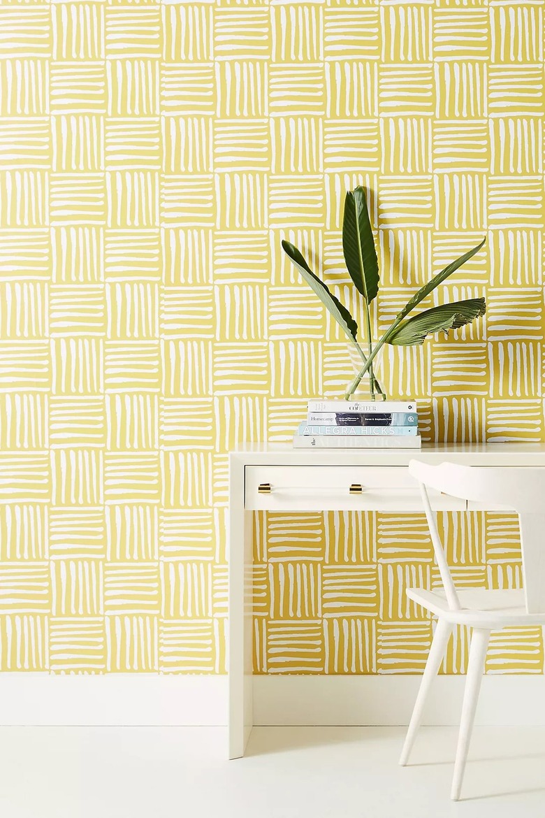 yellow home office with white and yellow wallpaper behind a white desk