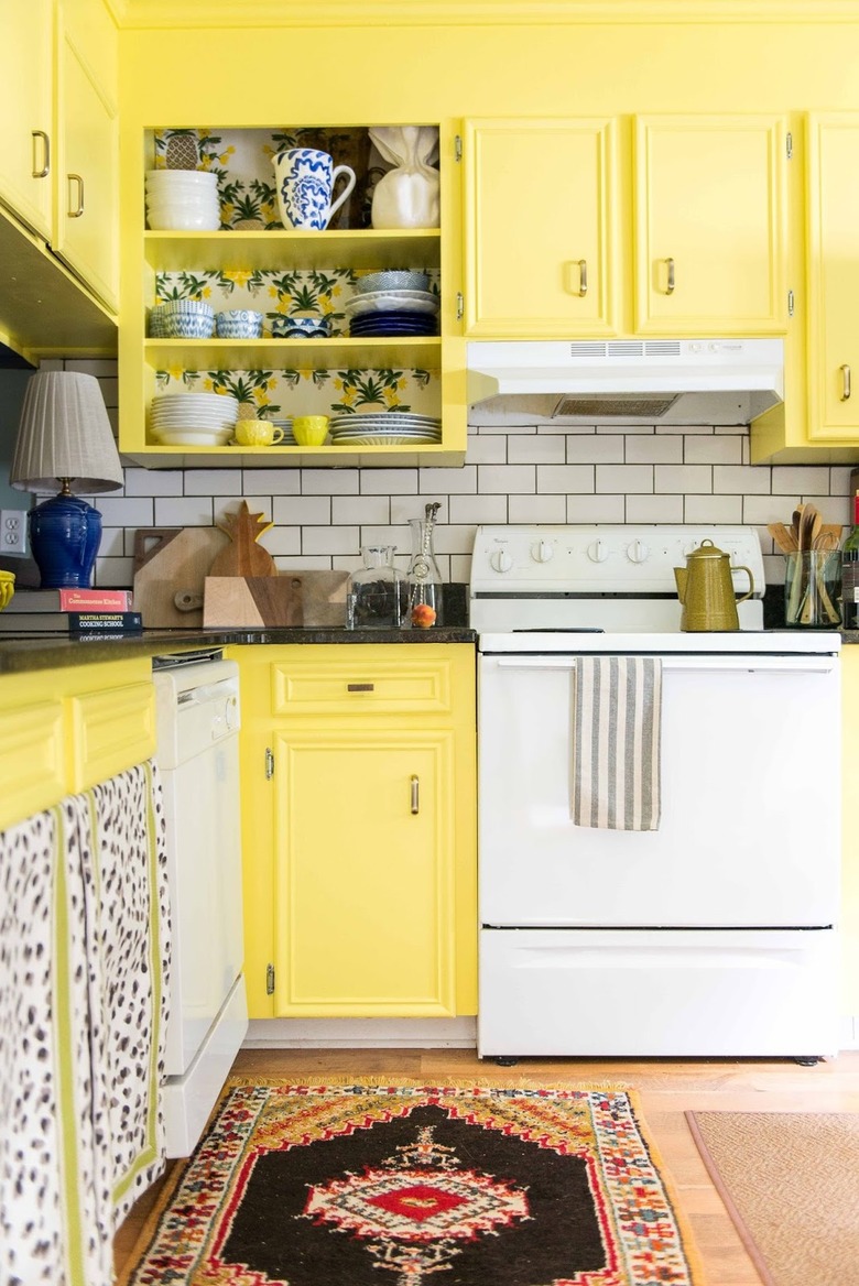 Bright yellow kitchen cabinets with white subway tile backsplash.