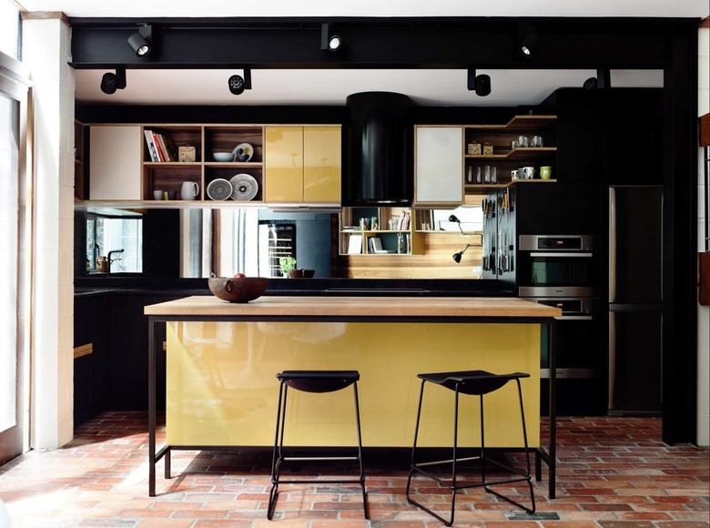 Dark kitchen with black wall paint and yellow cabinets.