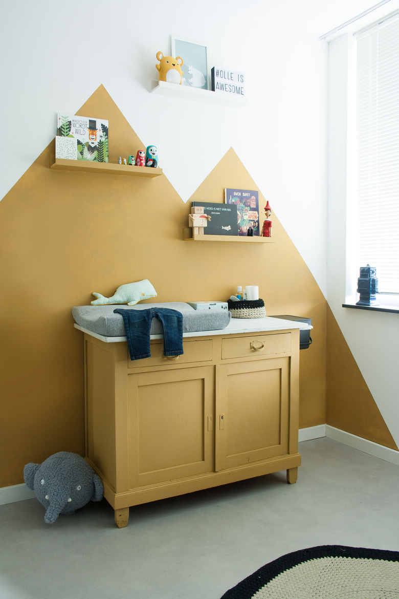 yellow nursery idea with color blocked mountains painted on wall and cabinet and shelves painted in same color