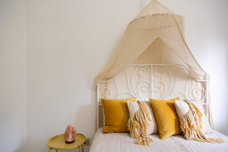 Yellow Room Ideas in Yellow and off white pillows, white bedding, canopy, white vintage bed frame, white walls.