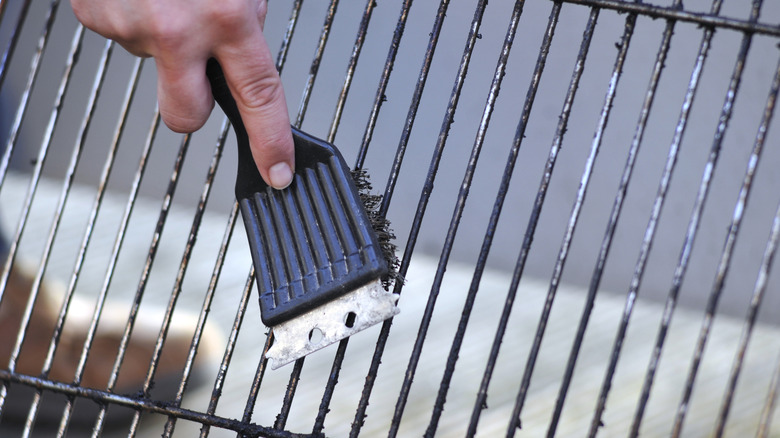 Close up of hand holding wire brush and scrubbing a grill grate