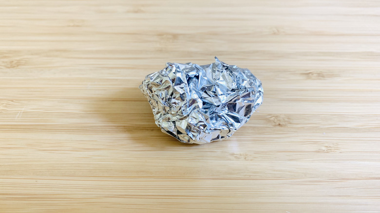 close up of aluminum foil ball on a wood surface