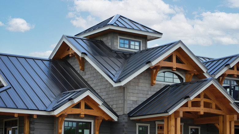 exterior of a home with a dark metal roof, gray shake siding, black windows,