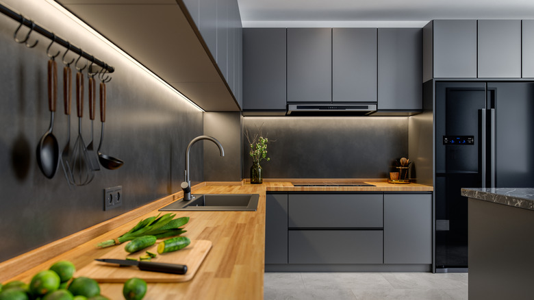 modern kitchen with charcoal flat front cabinets, wood countertops, and black appliances