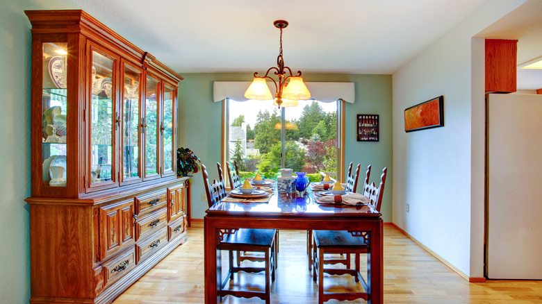 A dining room with a wooden table and chairs and a large, 3-door china cabinet.